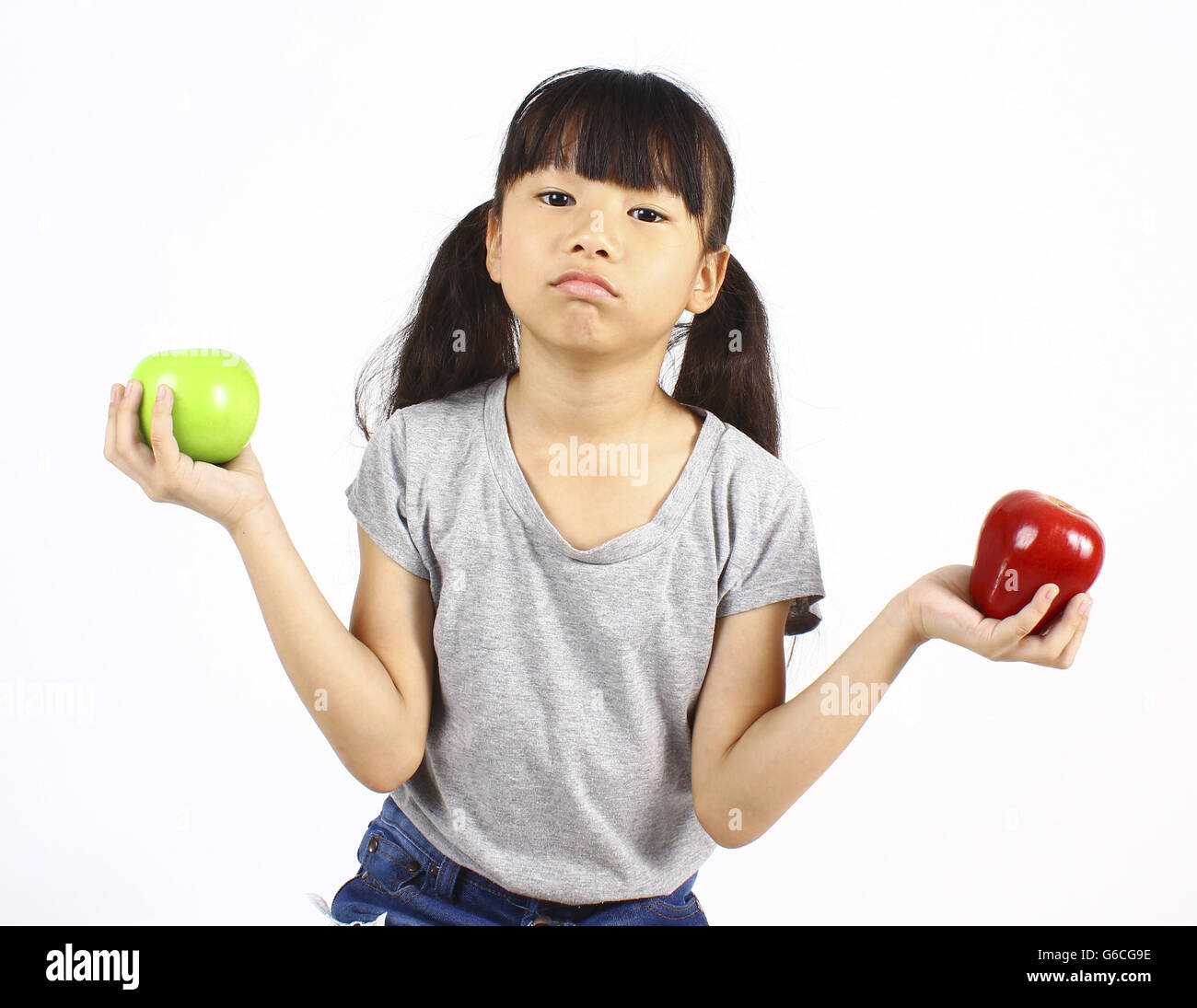 Cute girl holding red et green apple sur fond blanc. Banque D'Images