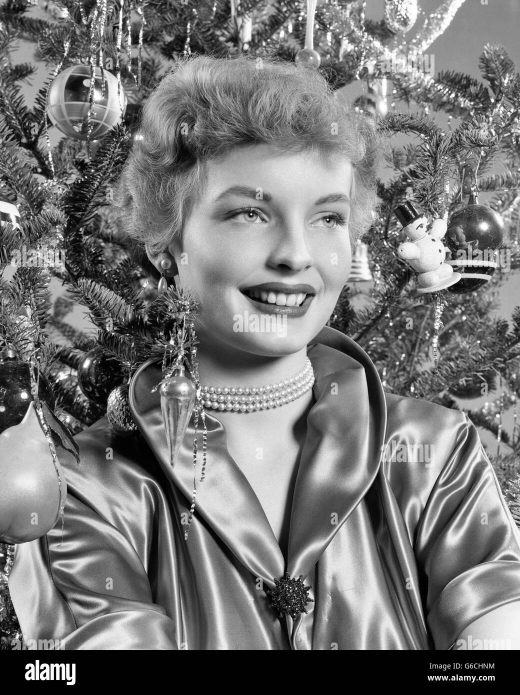 Années 1940 Années 1950 YOUNG SMILING WOMAN WITH CHRISTMAS TREE PORTANT CHEMISIER SATIN PEARL NECKLACE Banque D'Images