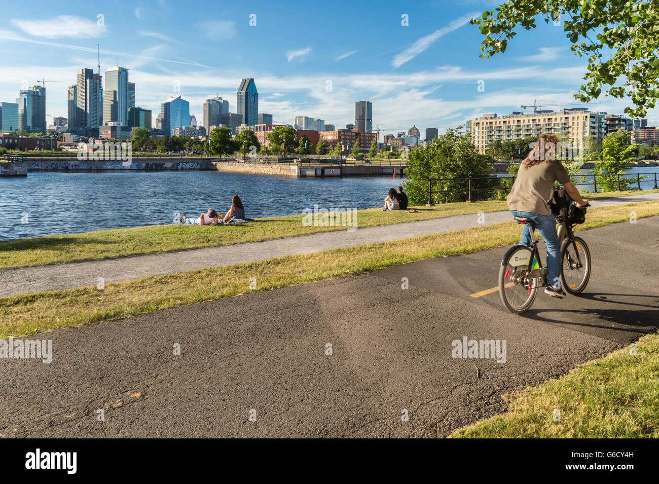 Homme de rouler à vélo sur la piste cyclable du Canal de Lachine à Montréal, avec en arrière-plan. Banque D'Images