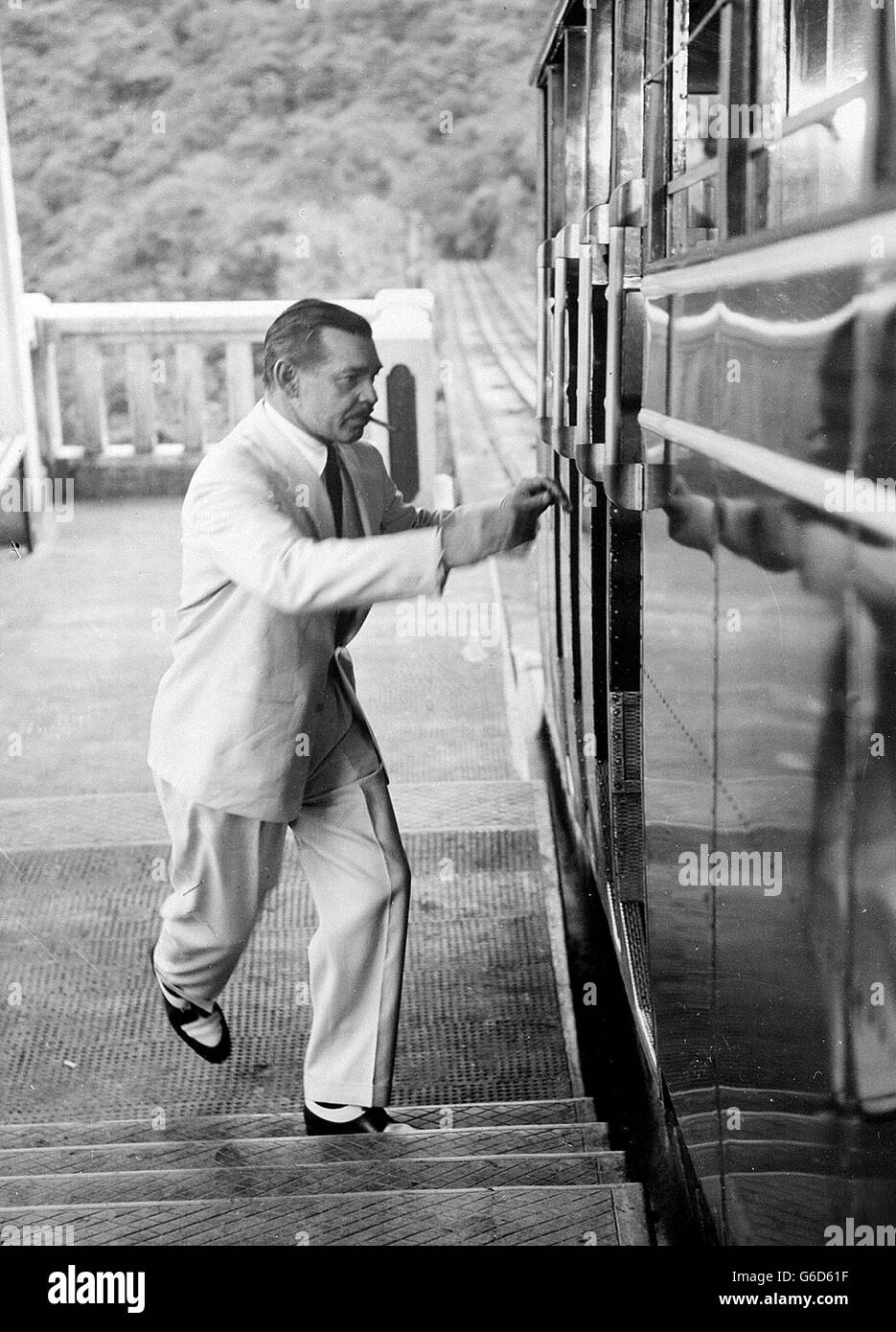 Clark Gable sprinting pour un tram de pointe à Hong Kong. Il était là pour faire le film « Soldier of Fortune » pour Fox du XXe siècle. Banque D'Images
