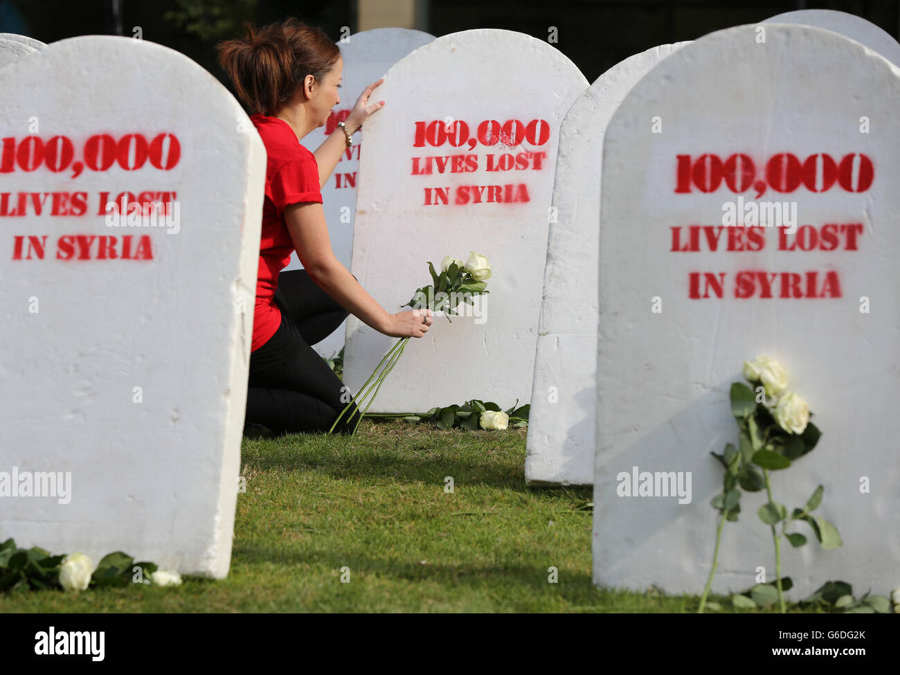 Un volontaire d'Oxfam s'agenouille devant des rangées de pierres tombales blanches symbolisant certaines des 100,000 vies perdues en Syrie, dans le centre-ville de Belfast, alors qu'Oxfam Irlande a appelé aujourd'hui les dirigeants mondiaux du G20 de cette semaine à Saint-Pétersbourg à intensifier leurs efforts pour un Solution politique pour mettre fin au bain de sang et aux souffrances du peuple syrien. Banque D'Images