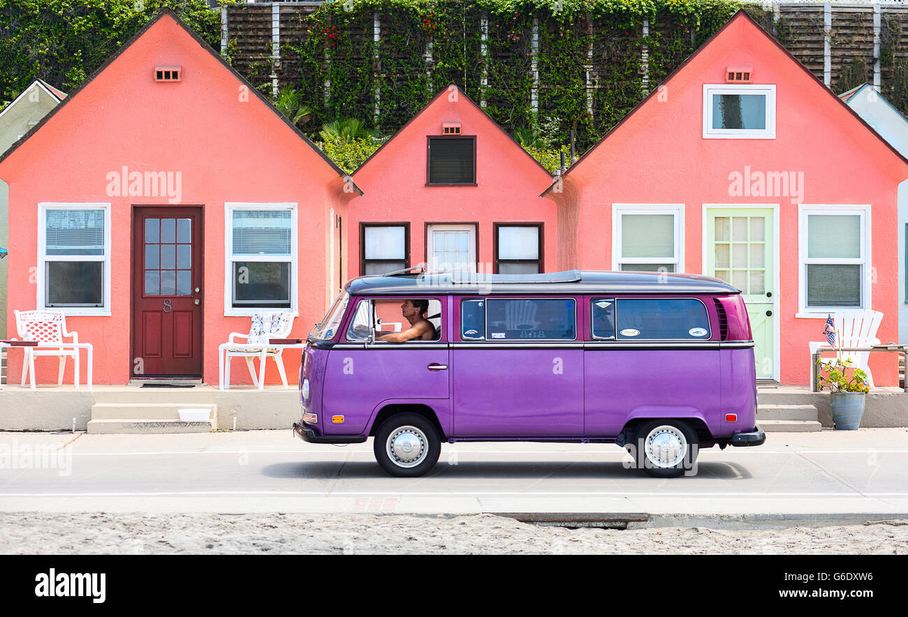 Un homme conduit un van Volkswagen violet sur une route en face d'une rangée de maisons roses à Oceanside, en Californie le 3 août 2014. Banque D'Images