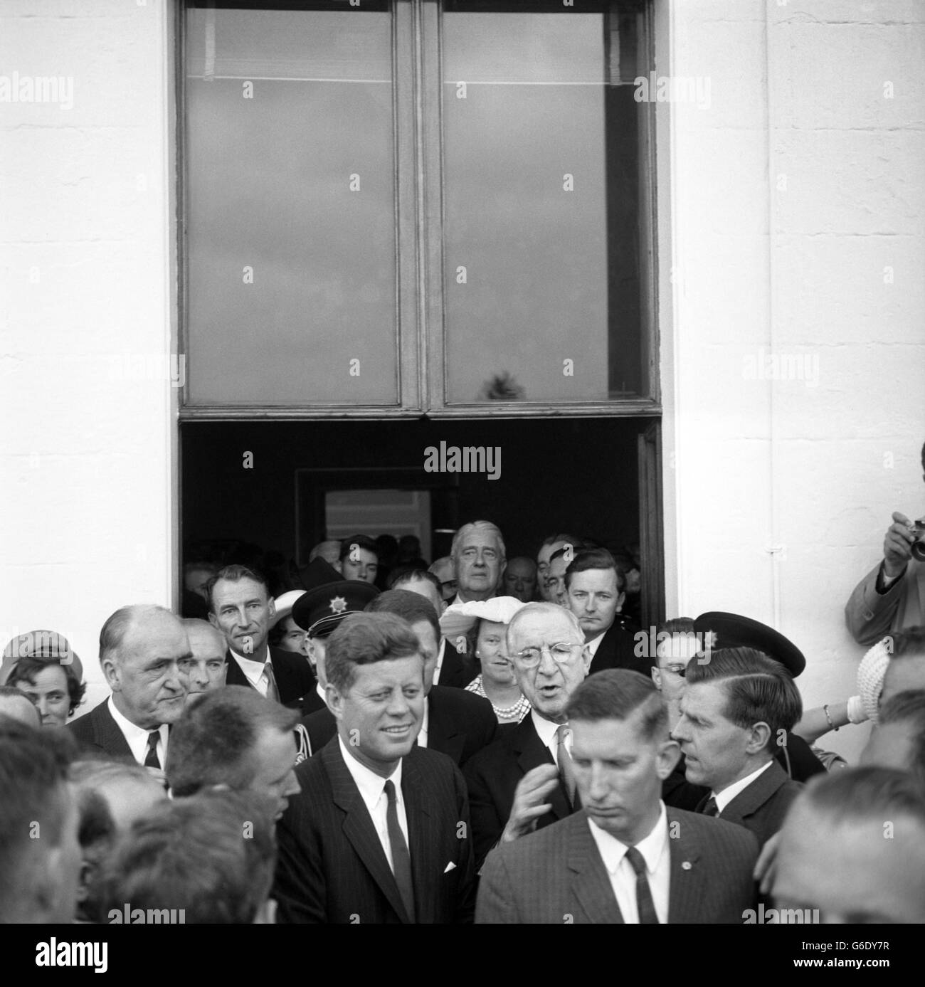 Incapable d'avancer ou de reculer en raison de l'écrasement des personnes qui veulent serrer la main, le président JOHN F. KENNEDY est entouré de G-hommes inquiets à une fête de jardin sur les pelouses du Phoenix Park, Dublin, résidence du président irlandais EAMON DE VALERA, qui semble en ce moment aussi anxieux que quiconque. Seul M. Kennedy parvient à avoir l'air détendu et souriant. À un moment, la foule autour de M. Kennedy était tellement emballée qu'elle a influencé chaque pas qu'il a pris le long d'une ligne de personnes dont il a serré les mains, et il semblait qu'une partie de la foule pourrait tomber dans l'une des deux piscines ornementales peu profondes Banque D'Images