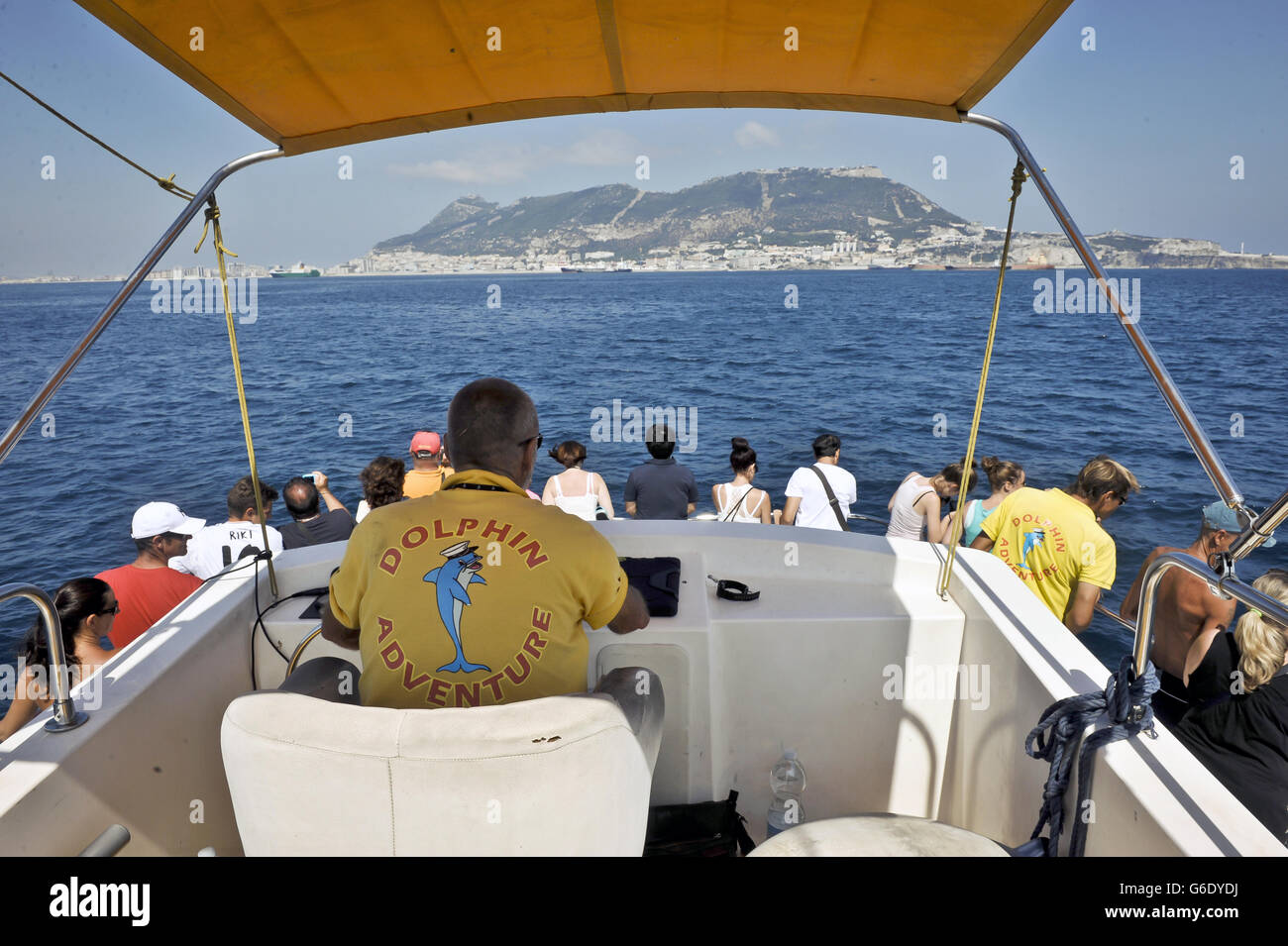 Voyage - Gibraltar.Un capitaine de bateau guide les dauphins qui regardent les touristes sur un bateau avec Gibraltar en arrière-plan. Banque D'Images