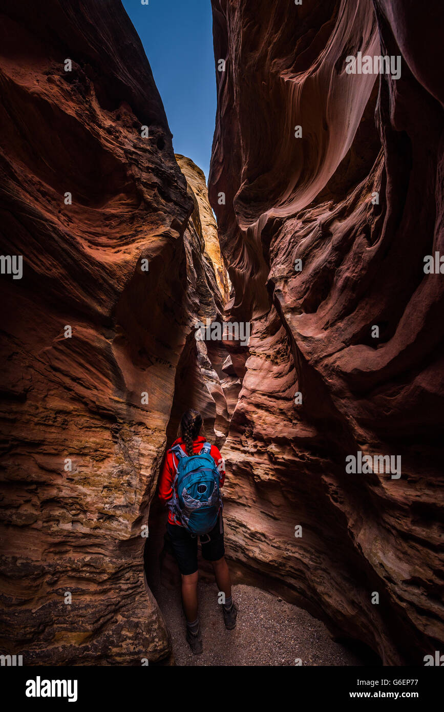 Jeune femme Backpacker explorant la fente étroite canyon petit cheval sauvage Goblin Valley Banque D'Images