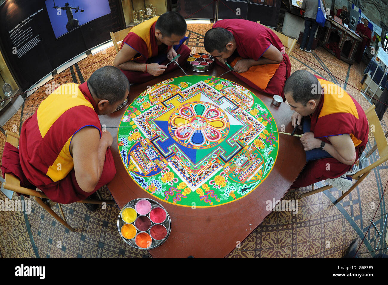 (Dans le sens des aiguilles d'une montre en haut à gauche) Kachen Choedrak, Ven Lobzang Thokmed, Kachen Namgyal et Kachen Lobzang Tuskhor, moines du monastère de Tashi Lhunpo, faisant un Mandala de sable de Chenrezig de compassion et de bonté dans le Chapitre House de la cathédrale de Salisbury. Banque D'Images