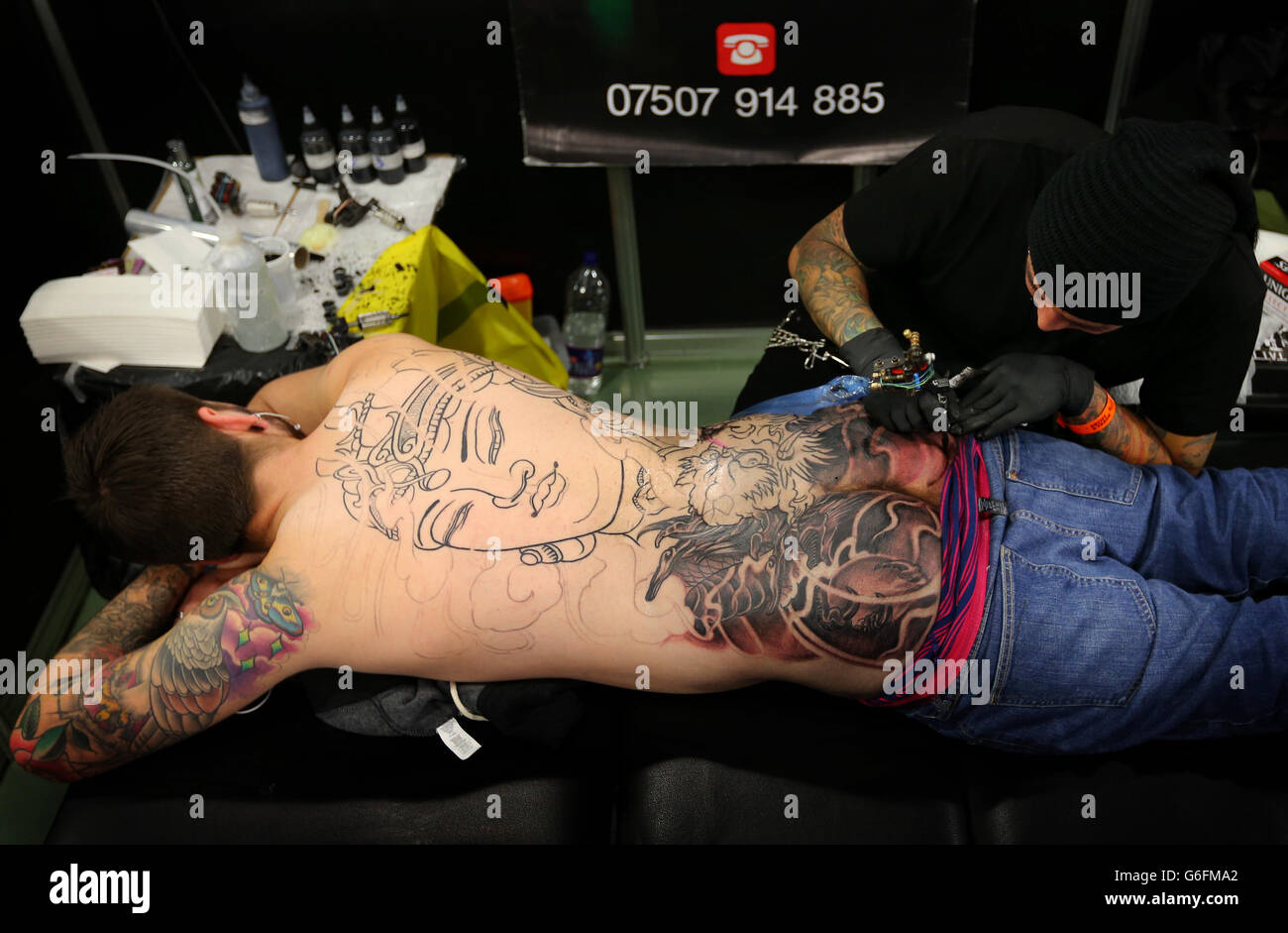 L'artiste de tatouage Leo Rios travaille sur les fesses d'un homme (nom non donné) pendant le Tattoo Jam à Doncaster Racecourse. Banque D'Images