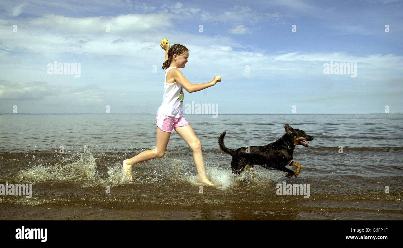 Ashleigh McCloskey, âgé de 11 ans, de Kilmarnock, bénéficie du temps chaud, sur la plage de Portobello, près d'Édimbourg, avec son chien Sauzee. * le temps de brûlage est prévu pour se poursuivre pendant au moins deux semaines, avec des millions de Britanniques se dirigeant vers des plages, des parcs et des jardins de bière. Certaines régions du pays devraient être encore plus chaudes que la Barbade, où le Premier ministre Tony Blair profite actuellement de son temps libre avec sa famille. La Grande-Bretagne a déjà connu le troisième mois de juin et juillet le plus chaud depuis 100 ans. Banque D'Images