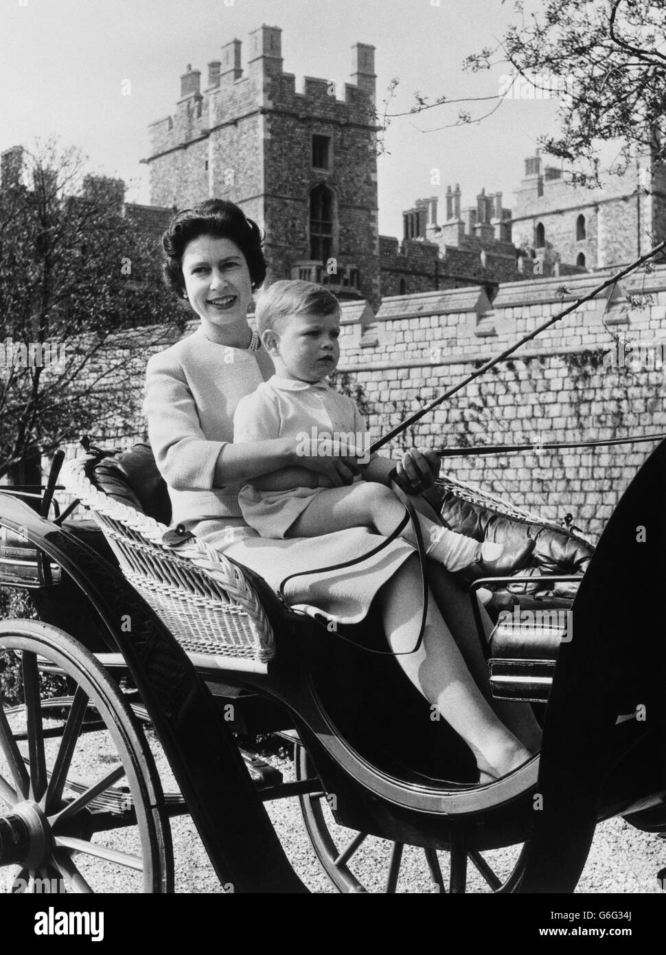 Le Prince Andrew est assis sur les genoux de sa mère tandis que la Reine fait un tour en calèche autour du château de Windsor. Banque D'Images