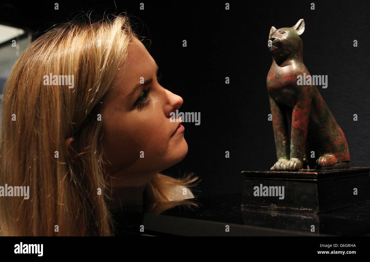 Un membre du personnel de Christie regarde un chat de bronze datant de la période Ptolemaic avec une estimation de £40.000-£60.000 qui fait partie d'une collection d'antiquités appelées les origines de l'art à vendre en octobre. Banque D'Images