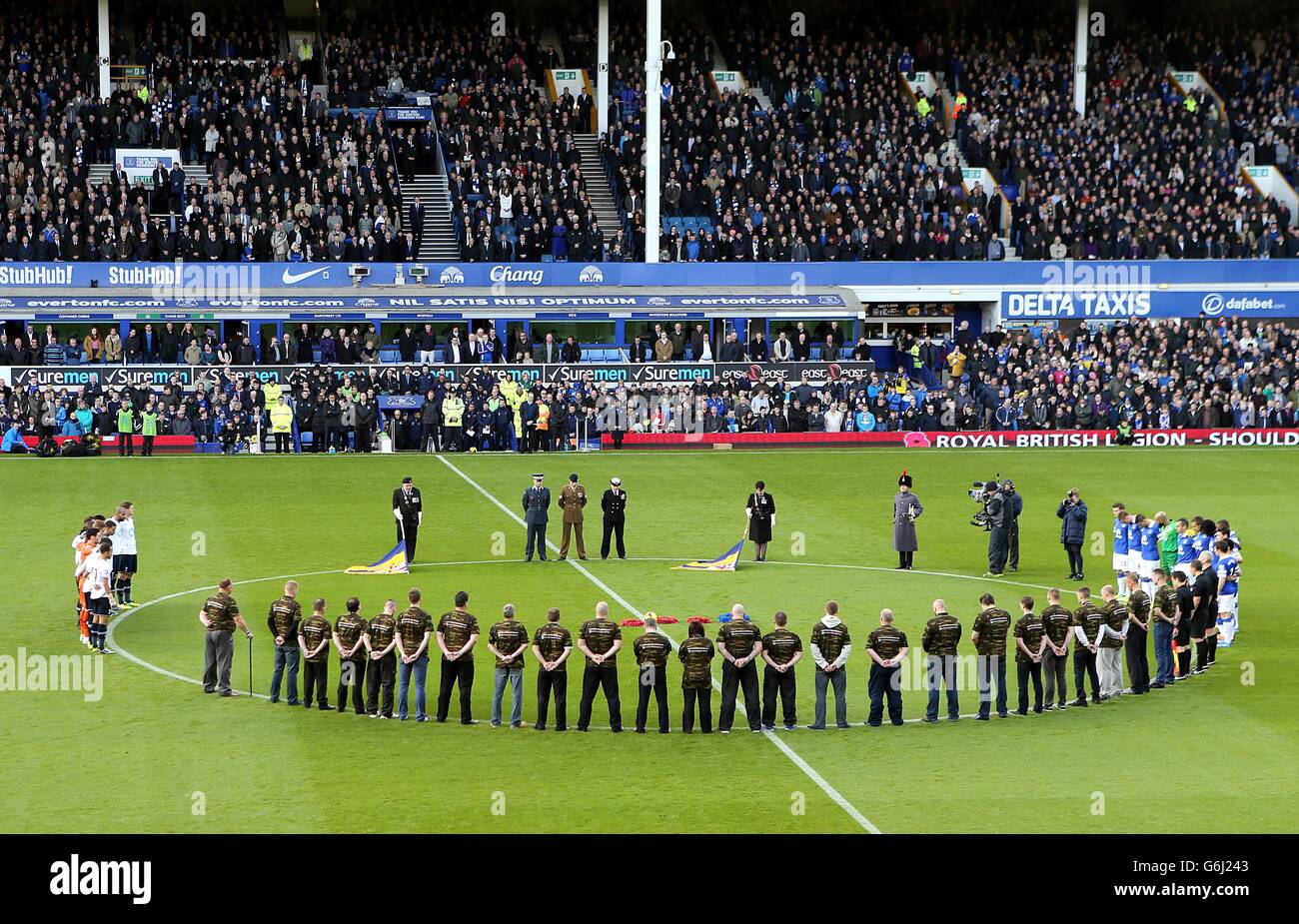 À droite, les participants se tiennent avec les joueurs d'Everton et de Tottenham Hotspur pour observer une minute de silence avant le coup d'envoi. Banque D'Images