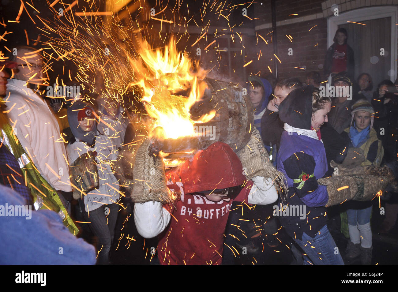 Les étincelles volent tandis que les enfants du village d'Ottery St Mary du Devonshire transportent le Tar Barrel traditionnel dans les rues du village pendant la nuit de Bonfire. Banque D'Images