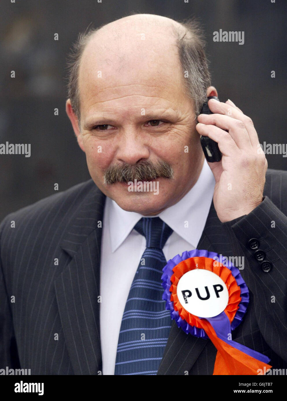 David Ervine, chef du Parti unioniste progressiste, parlant sur son téléphone portable lors d'une marche électorale à Belfast à l'approche de l'élection de l'Assemblée de l'Irlande du Nord.Le leader du PUP a reçu des gybes qu'il ressemble au personnage de jeu vidéo bien connu, Super Mario, bien qu'il ait dit qu'il aime le banneur. Banque D'Images