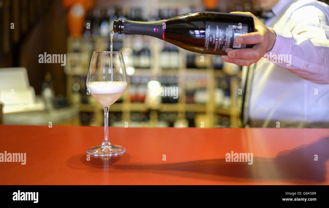 Barman verse du vin effervescent dans un verre sur le comptoir du bar. Banque D'Images