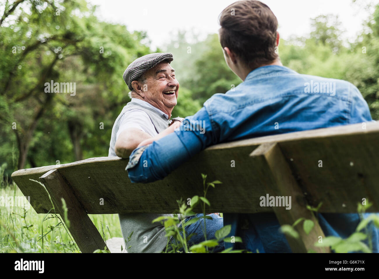 Laughing man assis sur un banc avec son petit-fils Banque D'Images