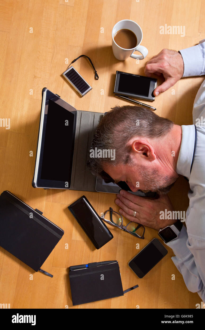 Vue de dessus de businessman lying on laptop entouré par la technologie Banque D'Images