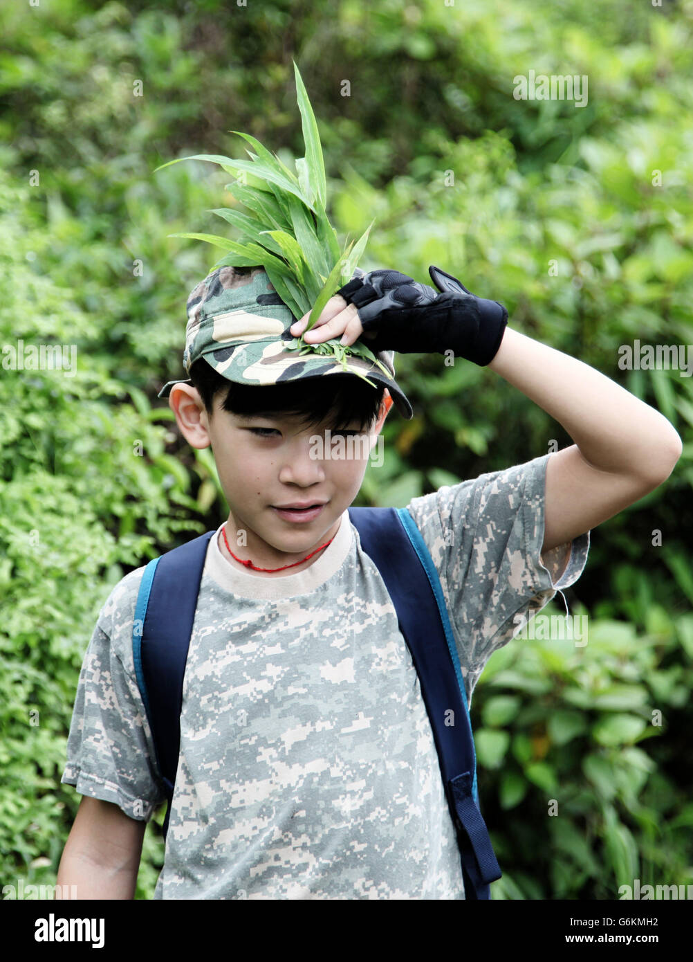 C'est une photo d'un petit garçon s'habiller comme un soldat. Il fait camouflage dans la forêt Banque D'Images