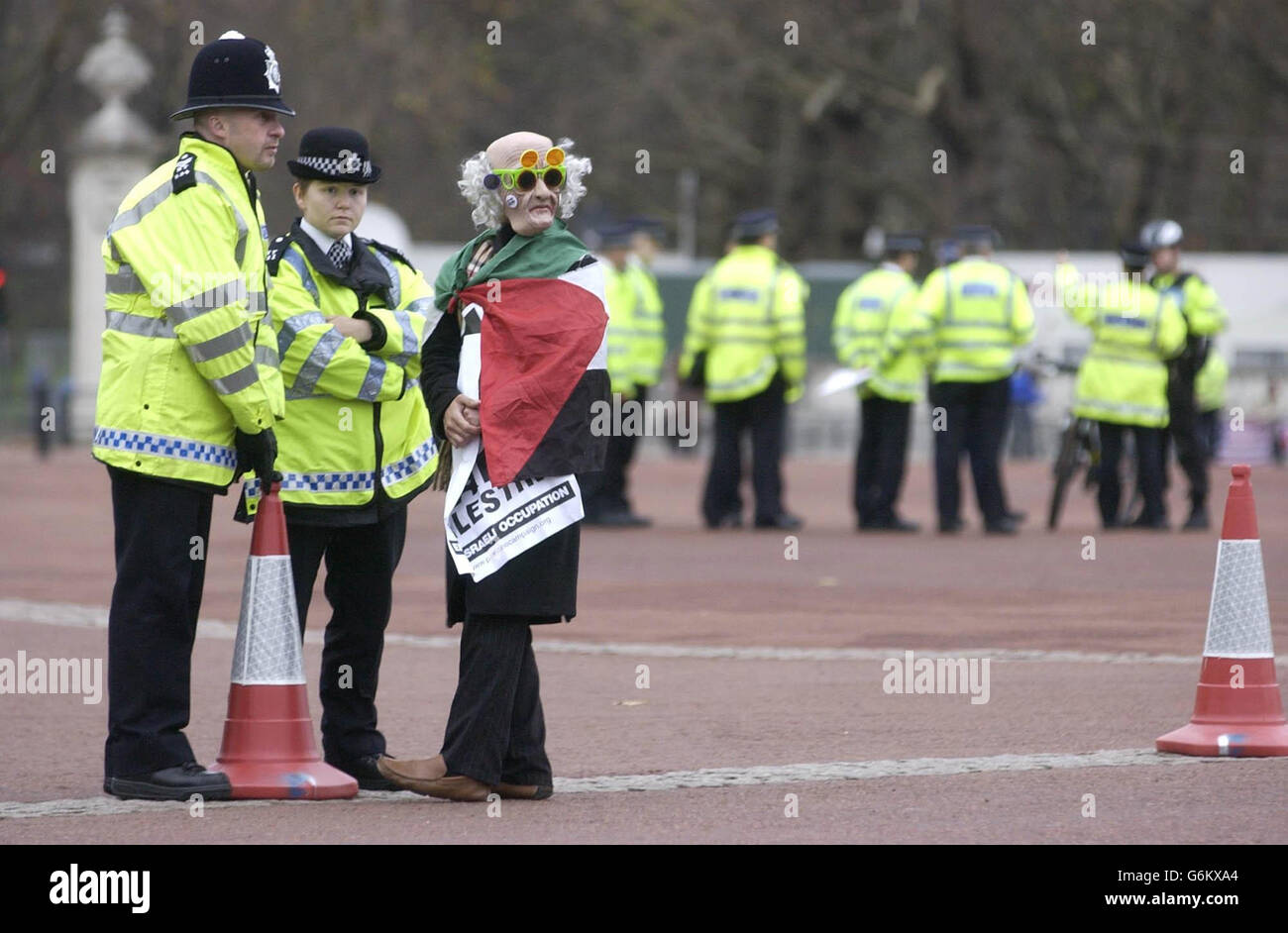 Un manifestant drapé dans un drapeau palestinien est arrêté par la police devant Buckingham Palace à Londres. Une importante opération de sécurité est en place dans la capitale pour la visite d'État du président américain Bush, qui reste au Palais en tant qu'invité de la Reine. Banque D'Images