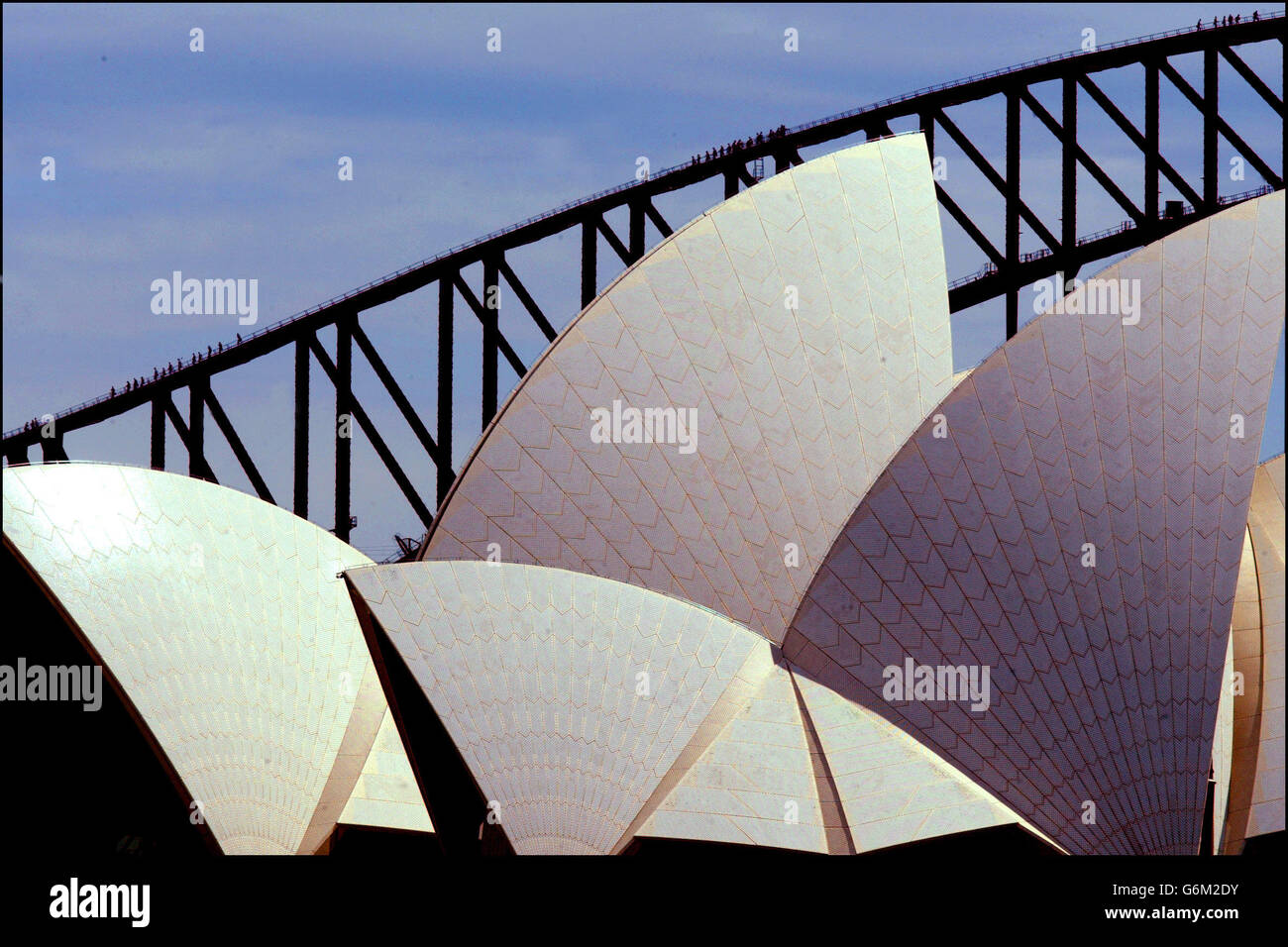 Les touristes qui grimpent sur le pont du port de Sydney ressemblent à des fourmis lorsqu'ils passent les voiles de l'Opéra de Sydney. Banque D'Images