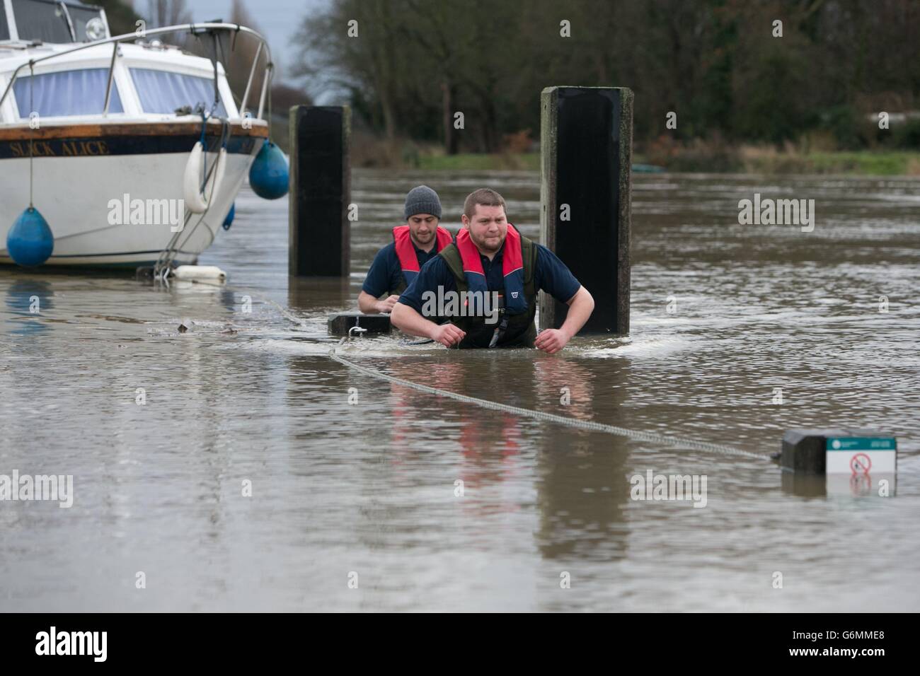 Dominic Webb (à l'avant) et Stuart Williams, de Lindon Lewis Marine, ont amarré à des amarres inondées à côté de la Tamise à Shepperton, Surrey. Banque D'Images