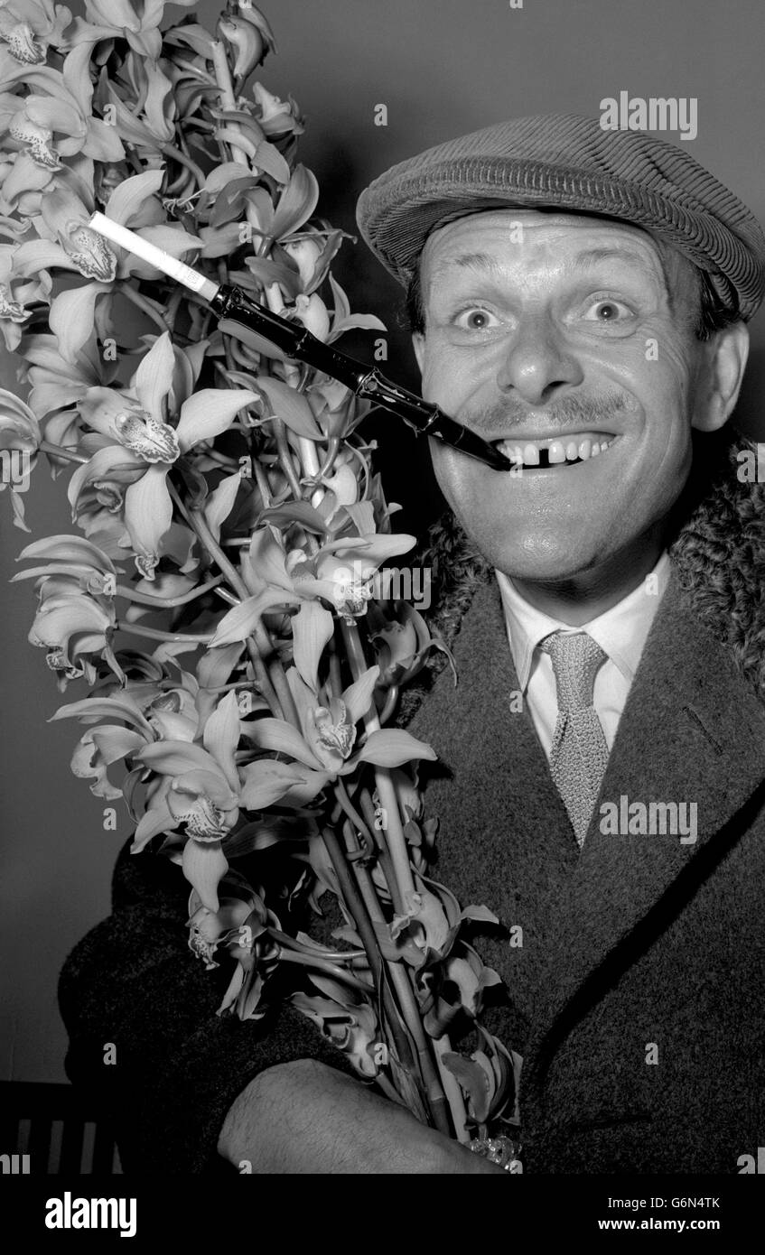 8 janvier - mort ce jour - 1990 TERRY-THOMAS 1952: L'élégant comédien de TV Terry-Thomas, qui présente un style sartorial distinctif, revient d'un séjour à Madère avec une casquette et un porte-cigarette étendu.Il porte un Bush d'orchidées pour sa femme, il est photographié à Southampton. Banque D'Images