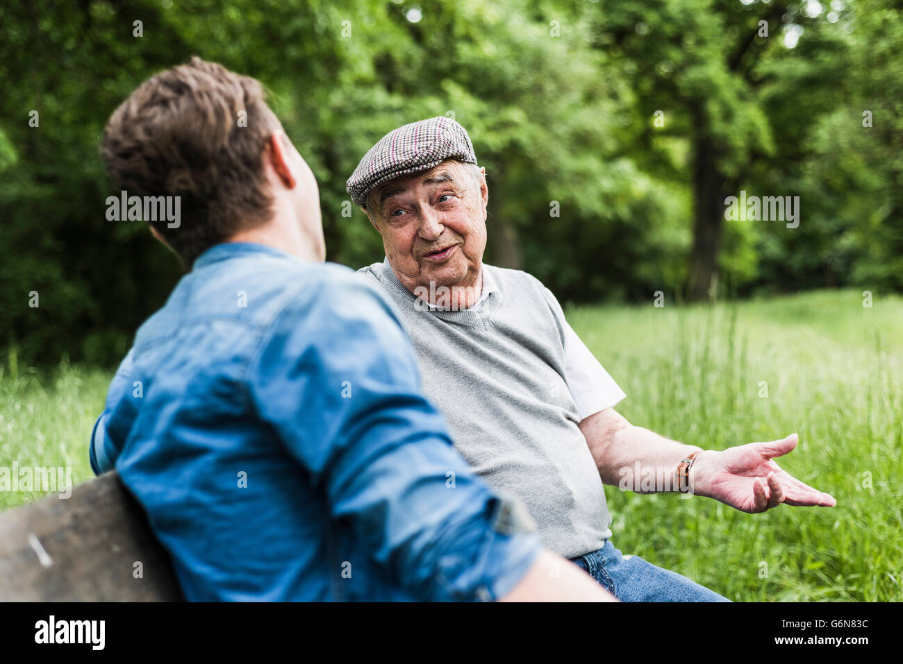 Portrait of senior man sitting on a bench de parler à son petit-fils Banque D'Images