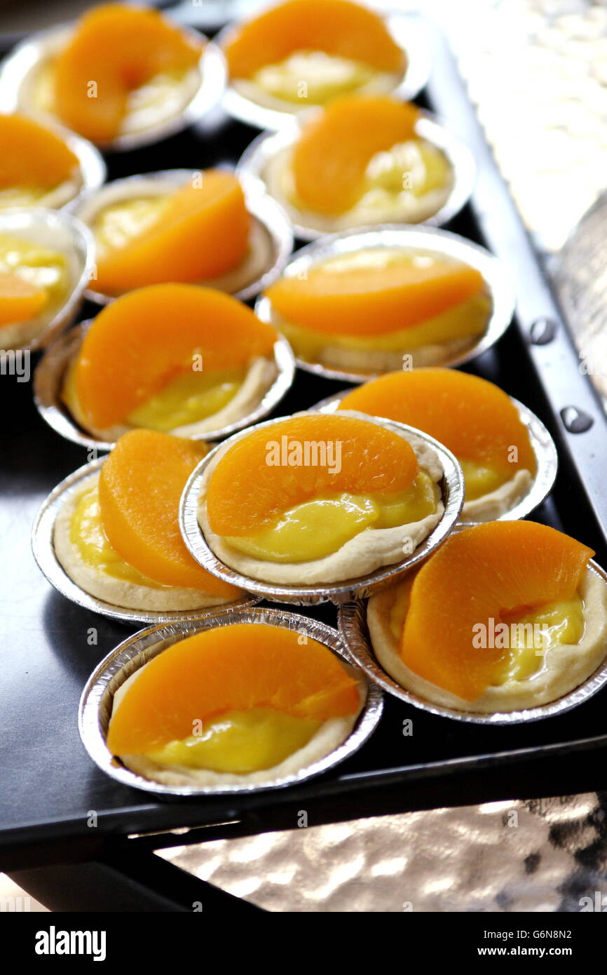 Close up of Peach tartelettes en noir plateau de service Banque D'Images