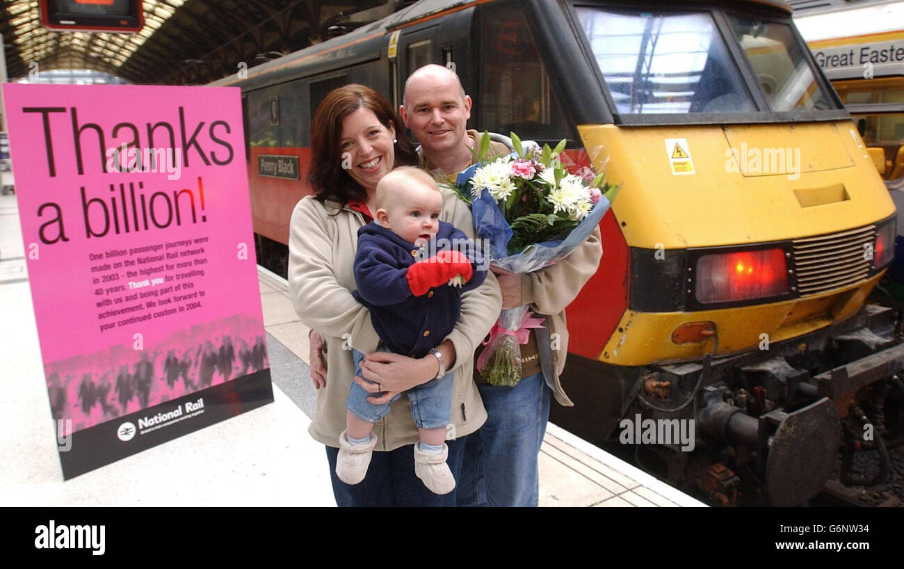 Steve Setford, l'épouse Lynn O'Malley et leur fils de huit mois, James, de Norwich, à la gare de Liverpool St à Londres, où ils ont reçu un billet de saison alors que l'industrie ferroviaire a célébré l'atteinte de la marque d'un milliard de passagers en 2003. Le ministre des Transports, Tony McNulty, a également dévoilé un « merci un milliard! » Poseur devant être mis en place dans plus de 500 des gares de Grande-Bretagne, remerciant les passagers pour leur coutume en 2003. Banque D'Images