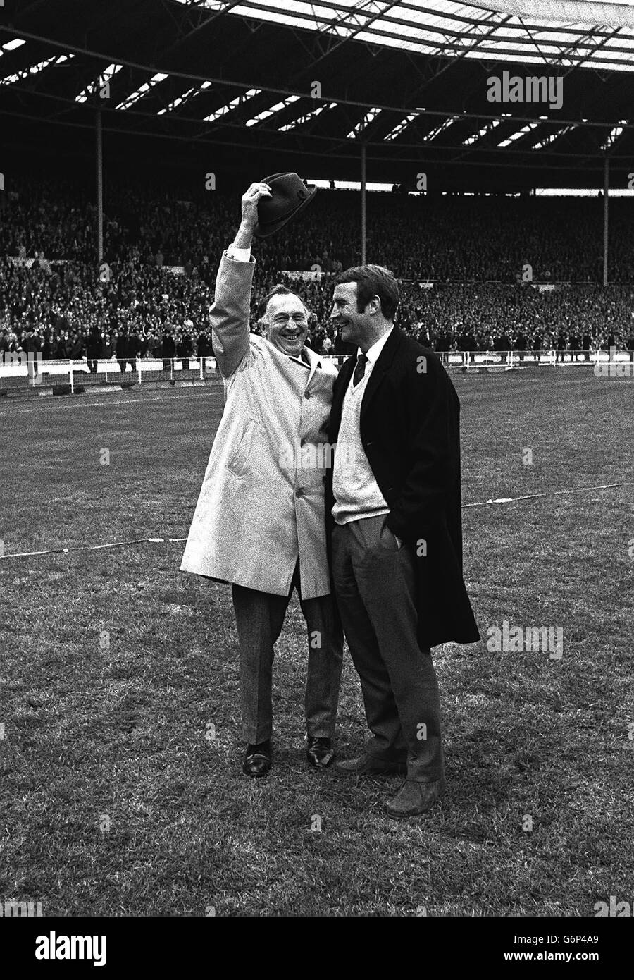 Joe Mercer (à gauche), le directeur du club de football de Manchester City,  levant sa casquette avec Malcolm Allison, l'entraîneur des équipes, sur le  terrain à Wembley après que leur équipe a