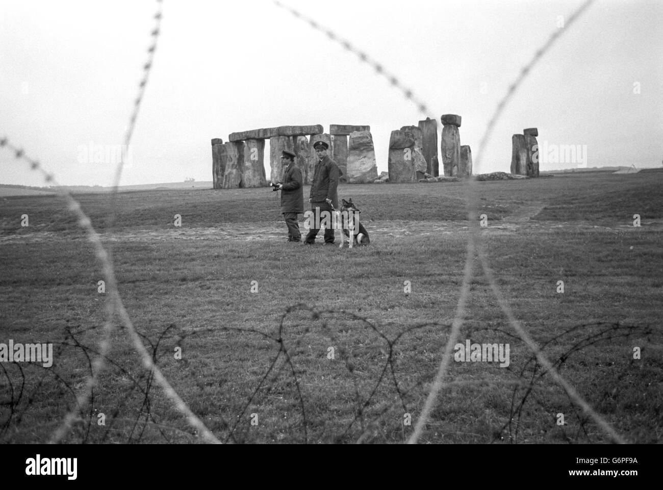 Deux gardes de sécurité et un chien de garde patrouillent la clôture barbelée entourant Stonehenge après le solstice d'été à 4,5 heures du matin, malgré les craintes que des centaines de hippies tentent d'envahir le monument pour organiser une célébration du solstice d'été. Banque D'Images