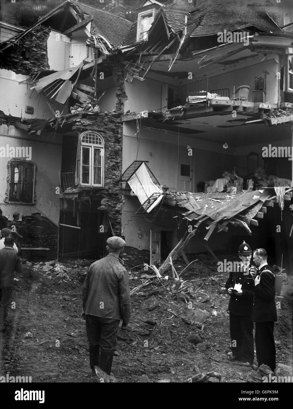 Devant les maisons ravagées par les inondations, la police utilise une radio-talkie-walkie pendant les opérations de sauvetage et de sauvetage à Lynmouth, Devon, dévasté.Tout au long de la journée, les troupes, la police et les organisations locales ont pris des mesures pour faciliter le travail de sauvetage et pour rétablir les services locaux.Douze personnes sont connues pour avoir perdu la vie, vingt-six sont encore disparues. Banque D'Images