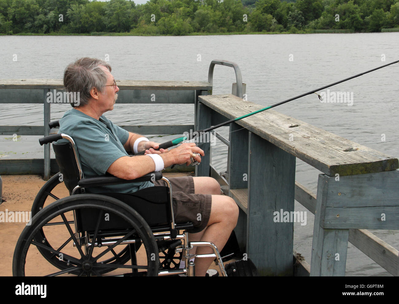 Homme en fauteuil roulant d'une pêche à la jetée de pêche accessible aux personnes handicapées Banque D'Images