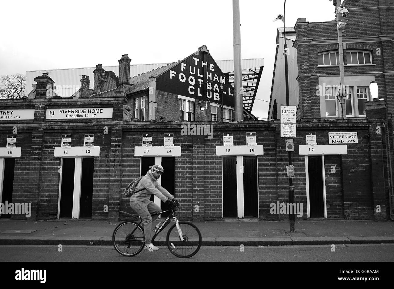 Un cycliste passe devant les tourniquets à Craven Cottage Banque D'Images