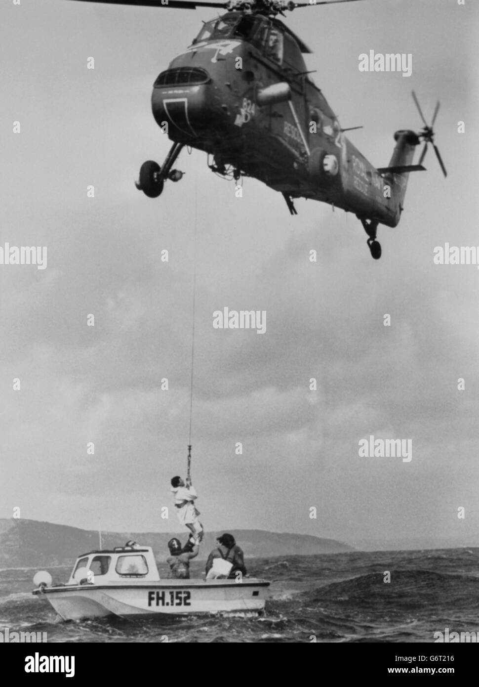 Simon le bon, la star pop de DURAN Duran, est aidé par un winchman de la marine alors qu'il est transporté dans un hélicoptère de la Royal Navy au large de Falmouth, le long de la côte sud de Cornwall, pour la deuxième fois en deux jours. Le bon et trois de ses membres d'équipage avaient navigué dans un bateau à moteur depuis le port de Falmouth pour inspecter les dommages à son yacht maxi de 77 pieds, Drum, qui a chaviré dimanche. Sur le chemin du retour au port, le bon s'est rendu compte qu'il serait en retard pour une réunion et a réussi à monter à bord d'un hélicoptère Wessex. Banque D'Images