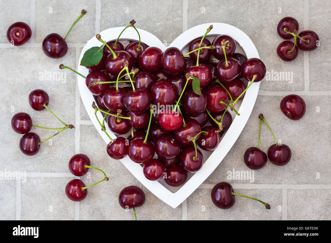 L'été humide frais cerise dans bol en forme de coeur Banque D'Images