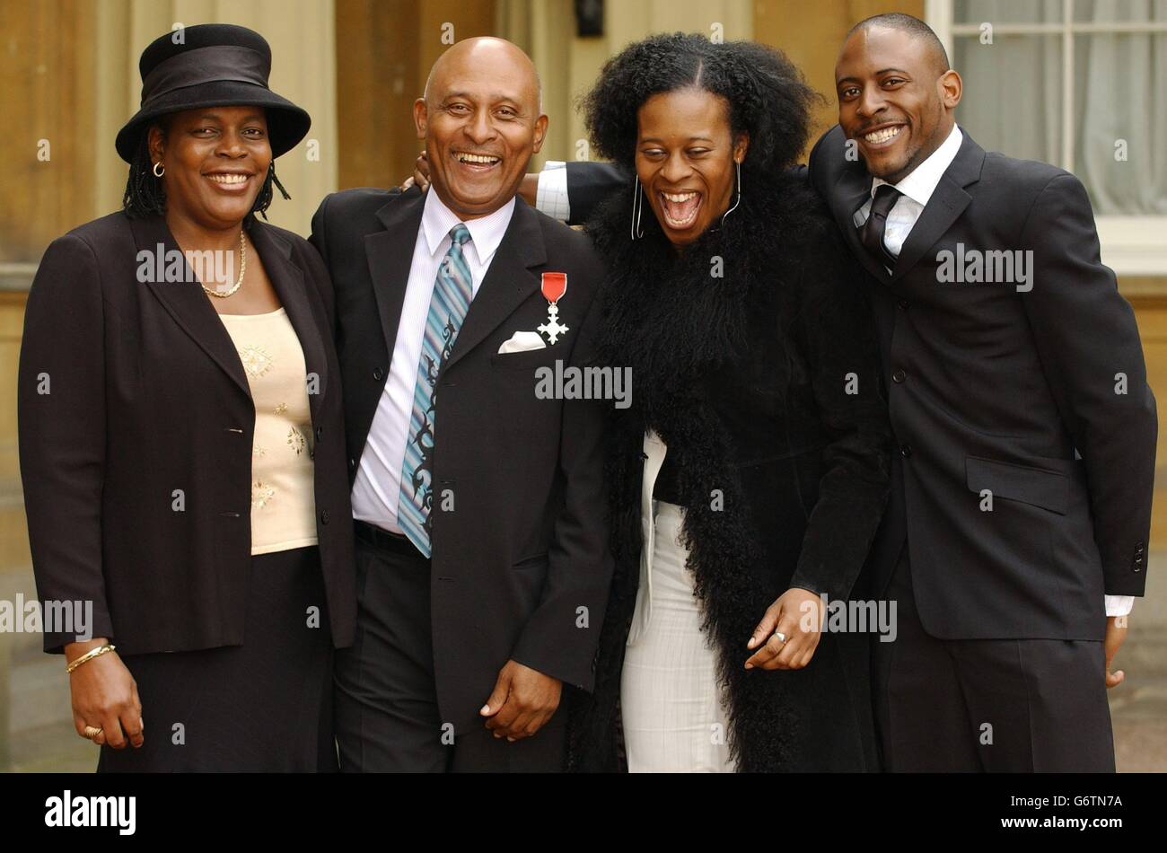 M. Albert Hamilton, après avoir accepté un MBE, pour des services au sport et à la communauté (fondateur des Commonwealth Sports Awards) de la Reine Elizabeth II au Palais de Buckingham. M. Hamilton est accompagné de Mme Fay Nesbeth (L), mère de son fils Nigel (R) et de sa fille (d'une ancienne relation) Arlene Cameron Hamilton. Banque D'Images