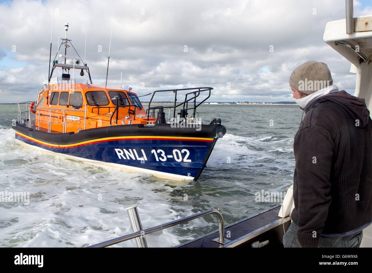 Photo inédite datée du 10/02/14 d'un pêcheur qui regarde le nouveau canot de sauvetage toutes saisons de la Royal National Lifeboat institution (RNLI), le Morrell, lors d'essais en mer au large de Poole, Dorset, car il est prévu d'arriver à la station de canot de sauvetage Dungeness dans le Kent aujourd'hui. Banque D'Images