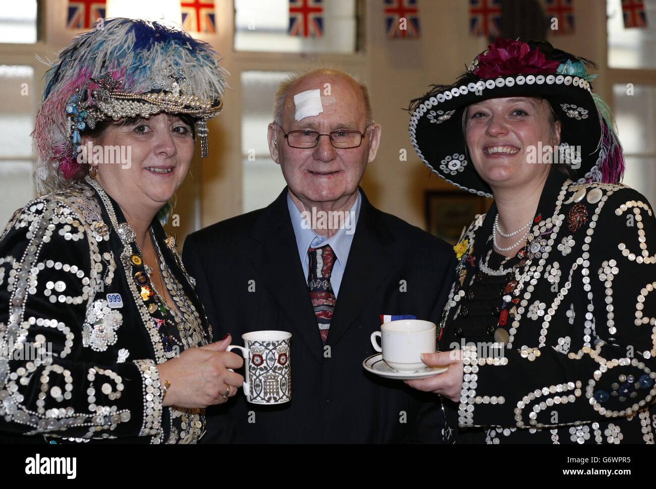 La reine de la petite enfance de Homerton (à gauche) et la reine de la petite enfance de Bow (à droite) servent du thé à Victor Holden lors de la fête de thé Contact The seniors organisée au Leytonstone & District ex-Servicemens Club à Londres. Banque D'Images