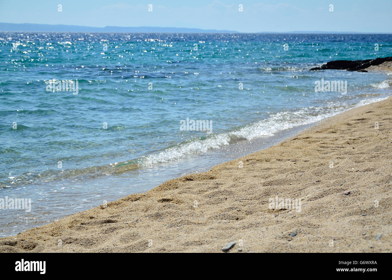 Mer vague mousseuse sur une plage de sable, à l'heure d'été Banque D'Images