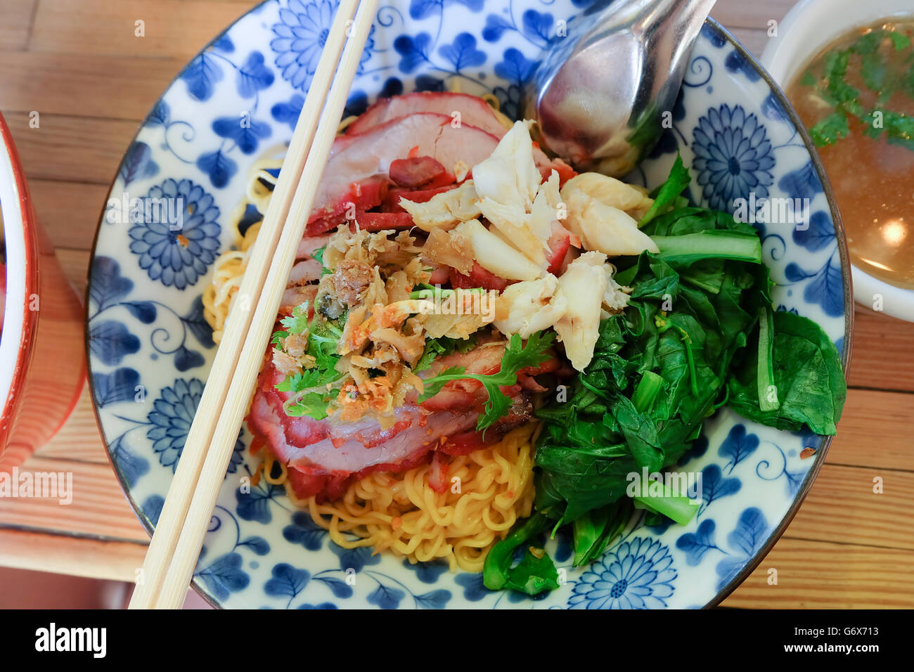 Les nouilles aux oeufs avec du porc aux poivrons rouges à la viande de crabe et pak choy. Local célèbre Thai style street food. Banque D'Images