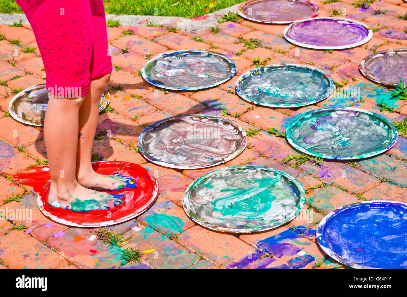 Enfants jouant des modèles colorés avec leurs pieds immergés dans la tempera colorés Banque D'Images