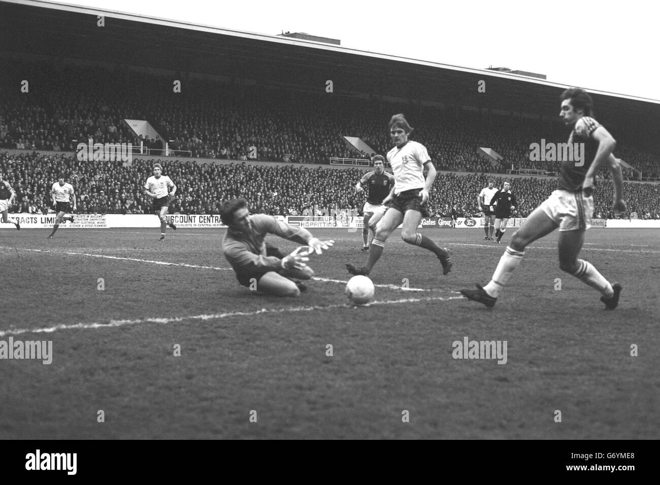 Le gardien de but de Wrexham Dai Davies plonge pour la balle dans son col de but à Upton Park lors du troisième match de la coupe FA contre West Ham United. Alan Devonshire (r) de West Ham est présent de près. Banque D'Images