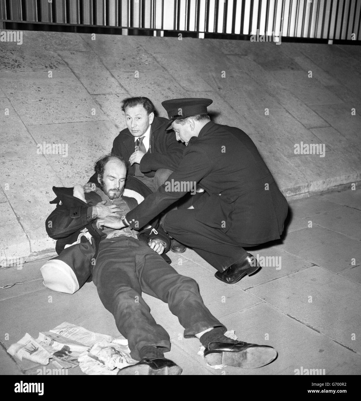 Un policier en uniforme se plie pour aider un homme qui semblait avoir été blessé dans des combats de manifestation à l'extérieur de l'ambassade des États-Unis à Grosvenor Square, Londres.Les manifestants, la plupart à la fin de l'adolescence ou au début des années 20, et au moins 2000, protestaient contre le blackade américain de Cuba, annoncé dans un discours du président Kennedy de Washington. Banque D'Images