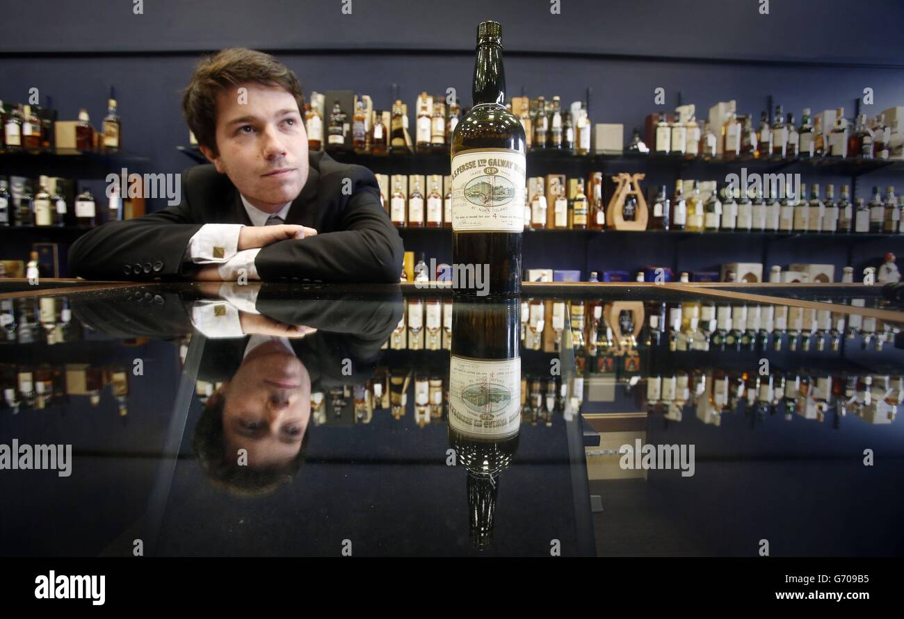 Joe Trotter, employé de McTear aux enchères, avec un whisky irlandais de 100 ans, vendu aujourd'hui aux enchères de McTear à Glasgow. Banque D'Images