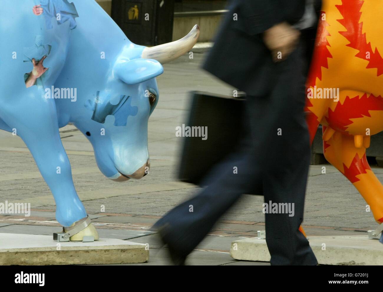 Un homme d'affaires passe devant deux des 100 vaches en fibre de verre grandeur nature disséminées autour de Manchester après l'arrivée de l'exposition d'art publique internationale CowParade dans la ville. Les expositions sur les bovins ont été créées par des artistes régionaux, locaux et de célébrités et seront trouvées en pâturage individuellement et dans les mini-troupeaux dans la ville jusqu'en septembre. En octobre, certains seront vendus pour recueillir de l'argent pour Manchester Kids, une association caritative qui finance des projets pour les enfants et les jeunes dans le Grand Manchester. Banque D'Images