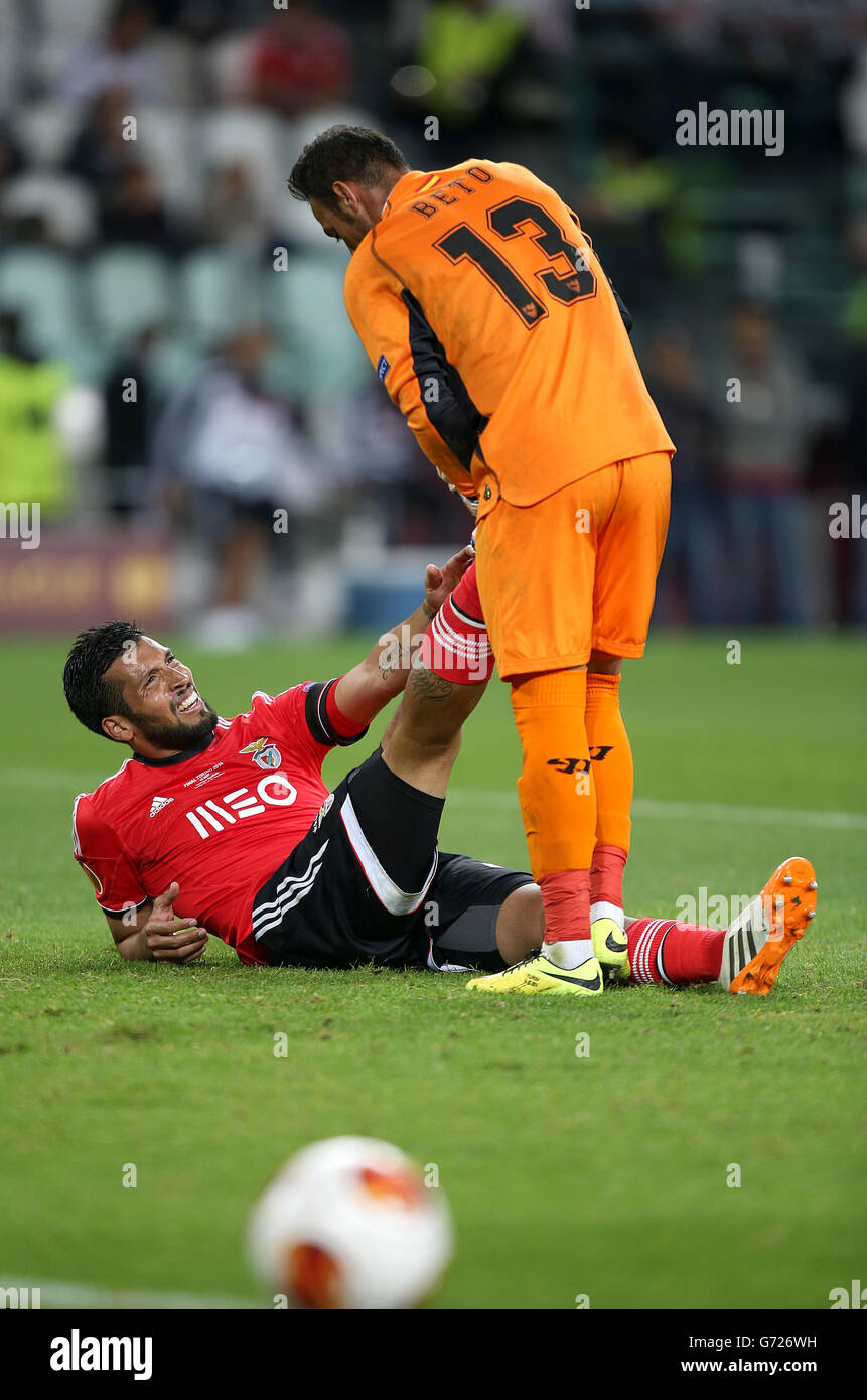 Le gardien de but de Séville Beto aide son adversaire Ezequiel Garay de Benfica qui se trouve frappé sur le terrain avec de la crampes Banque D'Images