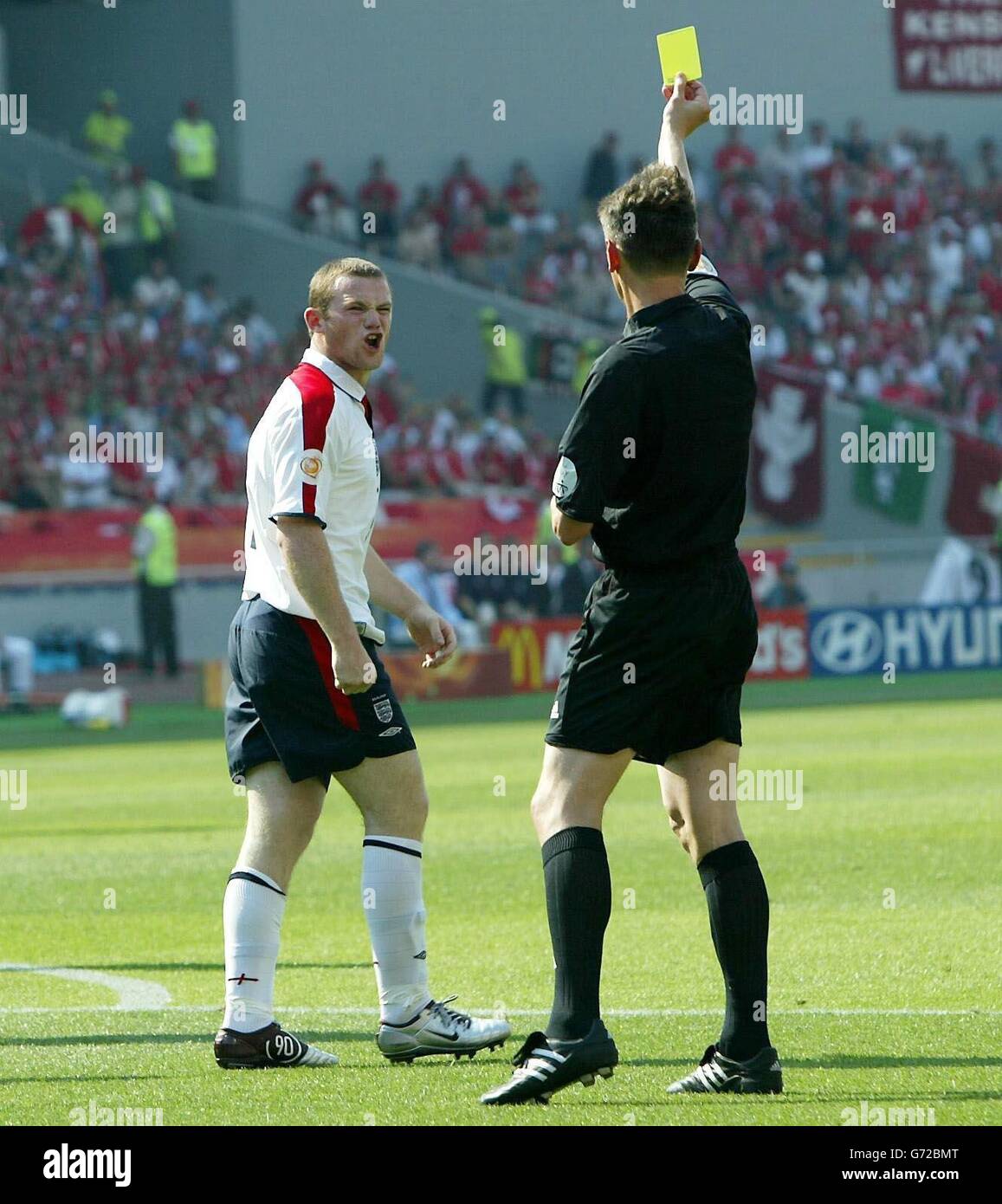 Le britannique Wayne Rooney reçoit une carte jaune de l'arbitre Valentin Ivanov après un défi sur le gardien de but suisse Jorg Stiel lors du premier tour de l'Euro 2004, du match du Groupe B au Cidade de Coimbra, Portugal. Banque D'Images