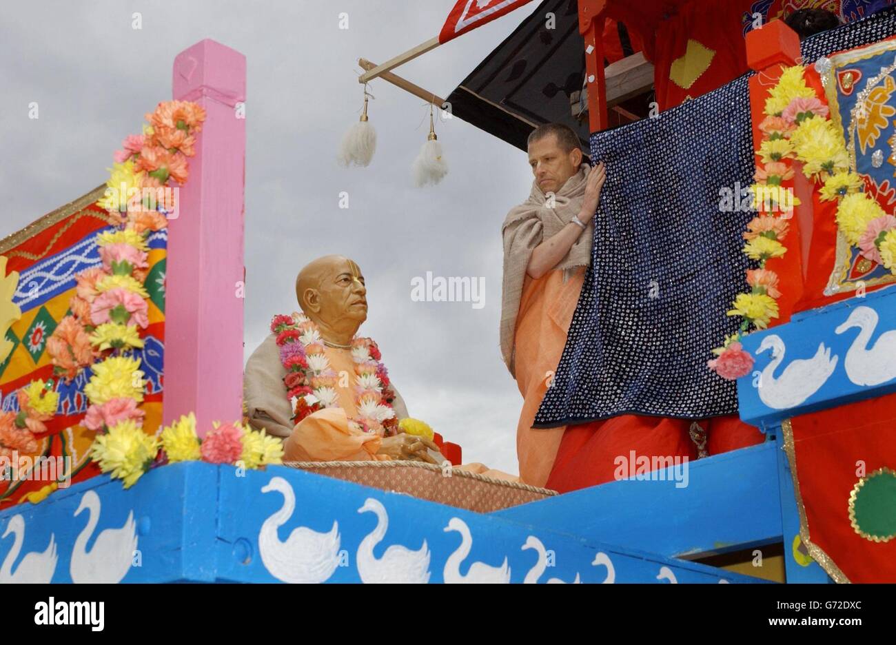 Un dévot Krishna regarde une sculpture sacrée du fondateur du mouvement religieux porté sur un char dédié à Lady Subhadra qui participe au Carnaval de Ratha-yathra dans le centre de Londres. C'est la première fois que le groupe a la permission de faire passer plus d'un char dans les rues. Banque D'Images
