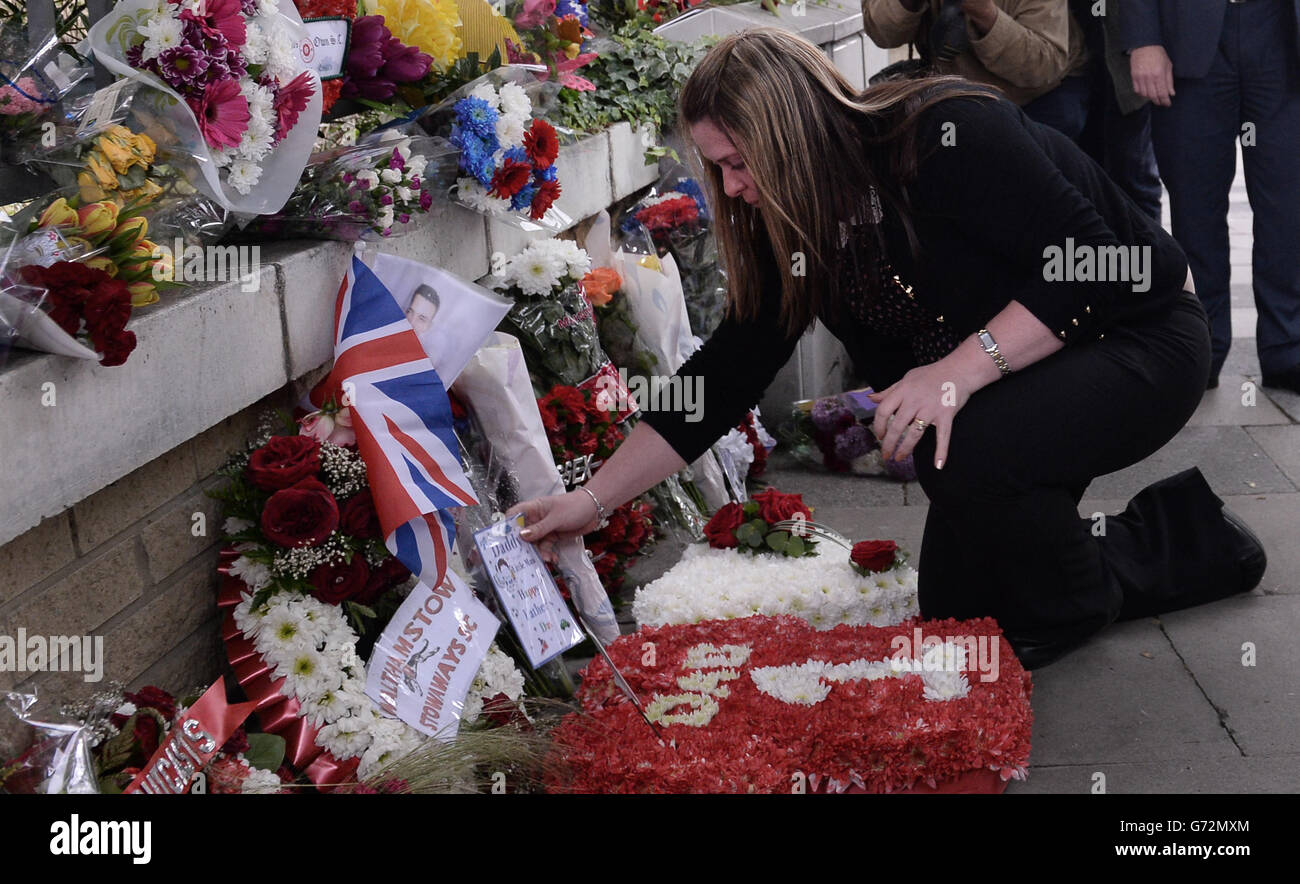 La veuve du soldat Lee Rigby assassiné, Rebecca Rigby (au centre), rend hommage sur les lieux de sa mort un an après qu'il ait été brutalement tué par les convertis musulmans britanniques Michael Adebolajo et Michael Adebowale à Woolwich, dans le sud-est de Londres, le 22 mai de l'année dernière. Banque D'Images