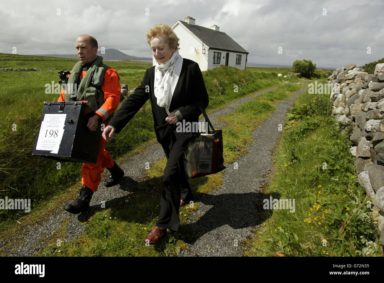 Le Sgt Val Murray aide Carmel McBride, président de Inishbofin, une île au large de la côte de Donegal, en Irlande, à voter alors que les insulaires se rendent aux urnes un jour plus tôt aux élections locales et européennes. Banque D'Images